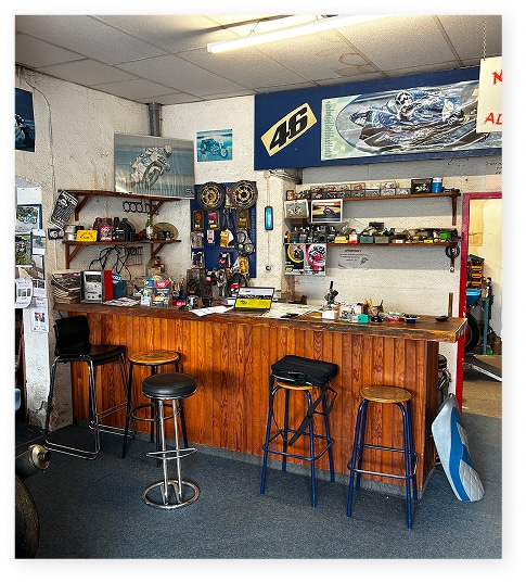 Comptoir d'un atelier moto décoré de posters Valentino Rossi 46, avec tabourets hauts et équipement mécanique.