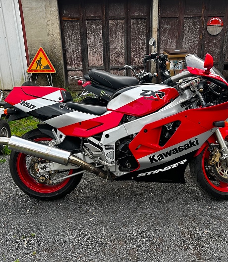 Kawasaki ZXR 750 Stinger : Moto Sportive Classique Rouge Moto Kawasaki ZXR 750 Stinger rouge et blanche, profil latéral avec marquages Stinger et ZXR devant un garage.